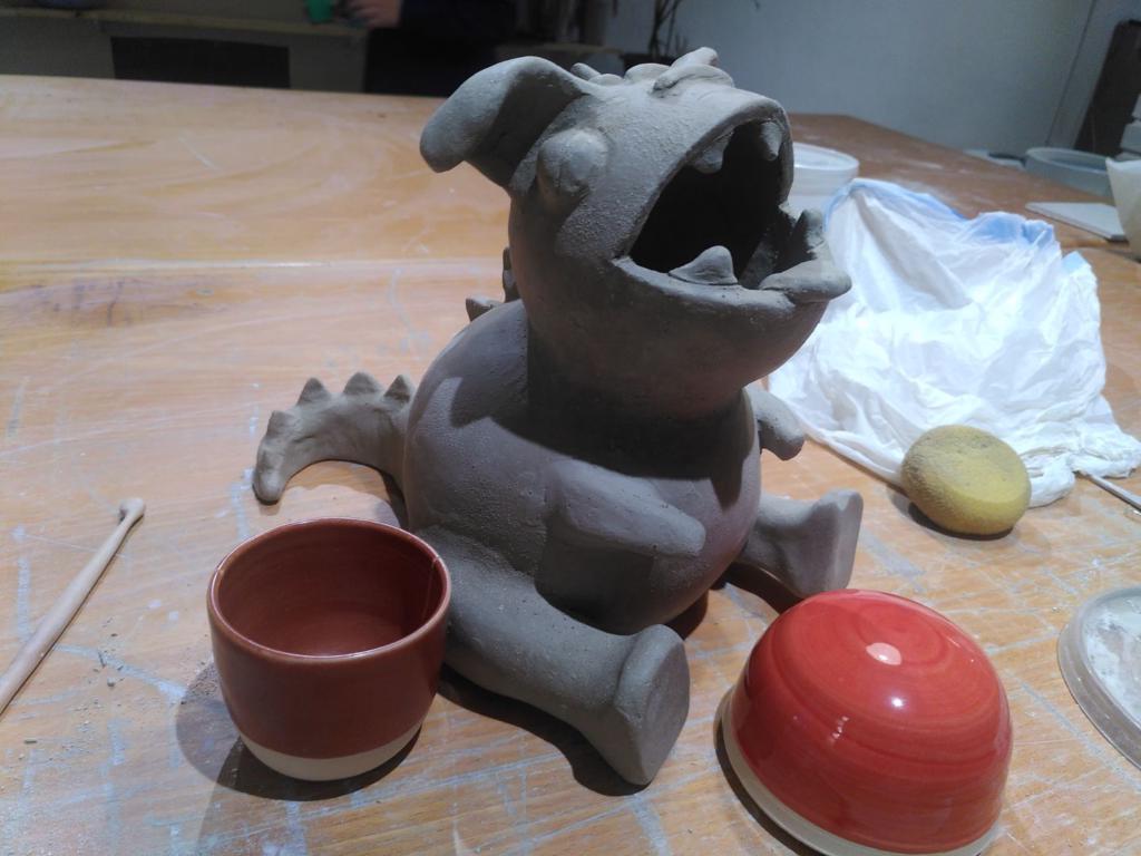 cute very round dragon, with arms, ears and spikes! Next to it are two bowls serving as a colour sample