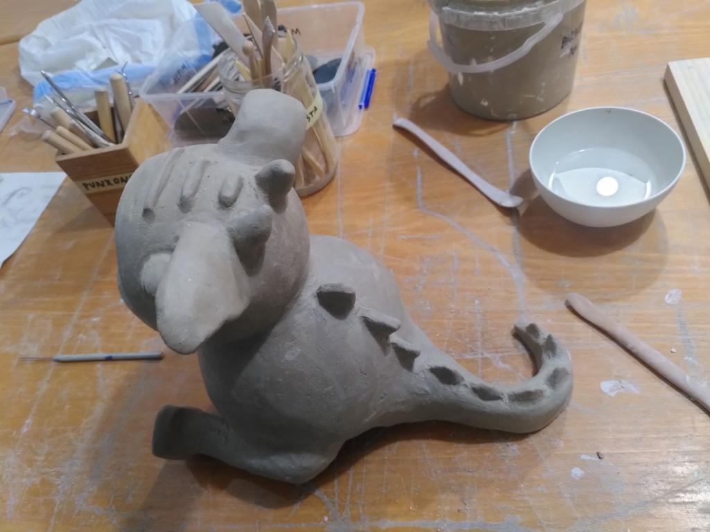 The cute round dragon from a back right angle, highlighting the back and the tail along with their spikes