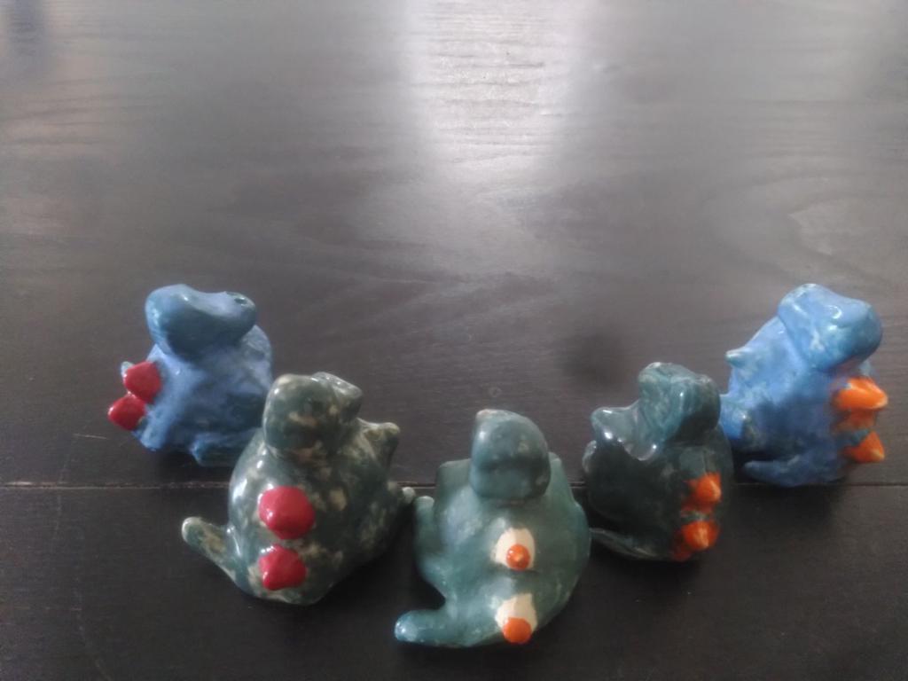 5 cute tiny dragons seen from the back, they form a half circle looking at the centre.