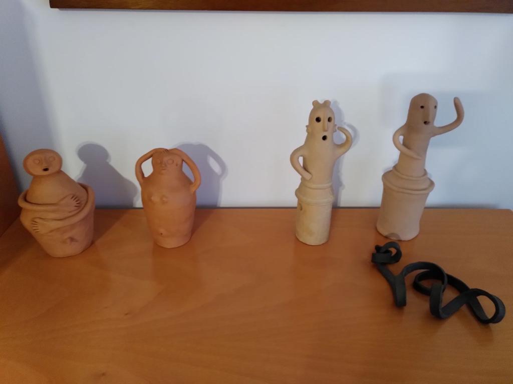 Picture of 4 humanoids on a flat surface, the two to the left are quite round and have a bit of a Pre-Columbine influence.
The two to the right, are the Haniwa Terracotta Dancers, one is an official replica, the other one was made afterwards to accompany its sibling.
In front of them there is a black knotted stripe, also made out of clay, by a friend who is a local potter.