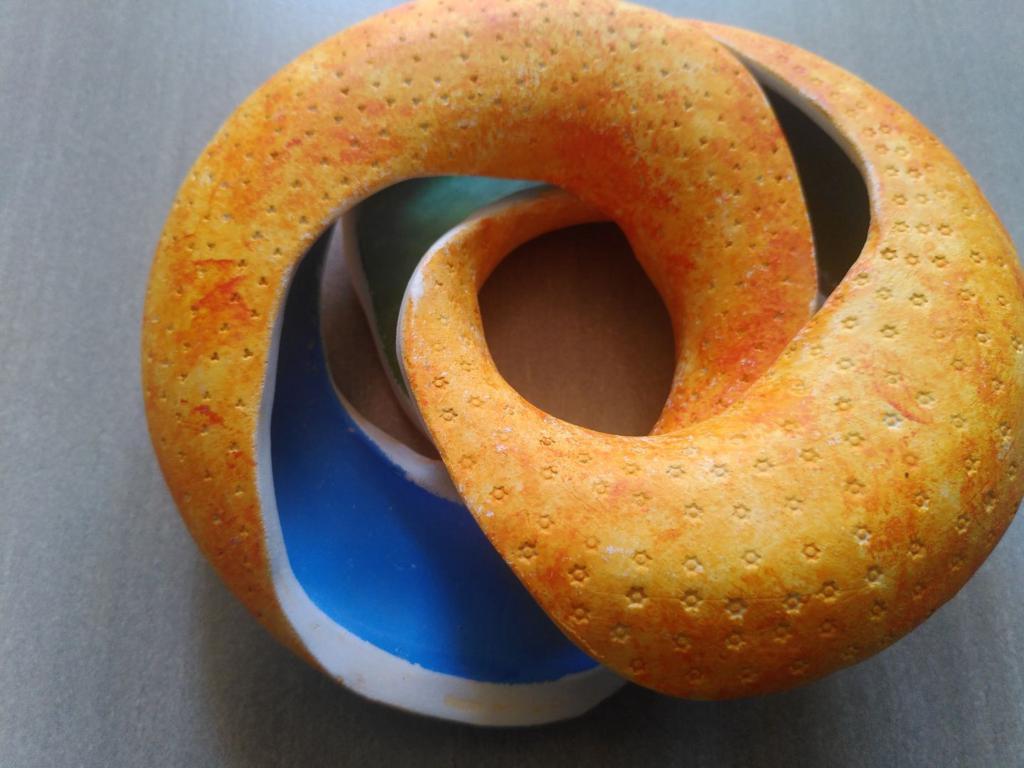 The doughnut, half open, so the outer orange is visible and also the inside is visible, with one piece being blue and one piece being green.