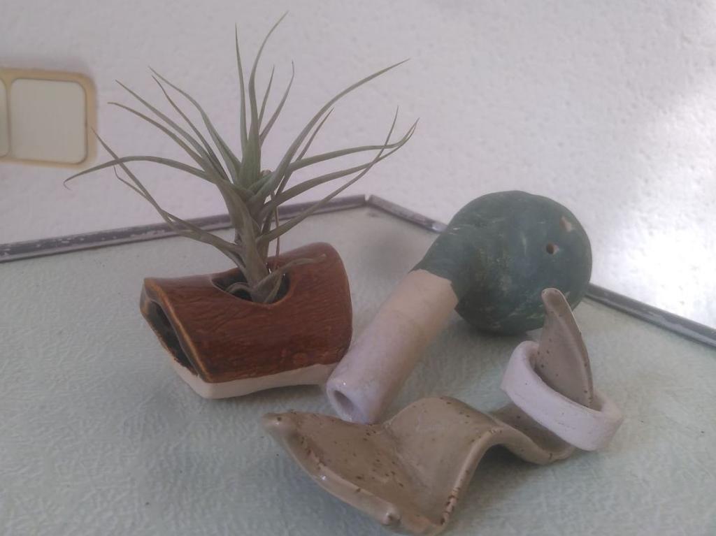 A close up of three different pottery pieces. the ocarina, with a spheric body with three holes and a blowing tube.