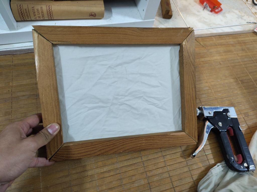 A wooden frame that holds a piece of cloth, it will be used to pick up pulp to recycle paper.