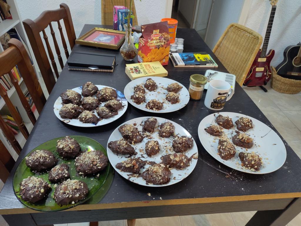 A table with 5 plates of Lebkuchen, glazed with chocolate and topped with almonds.